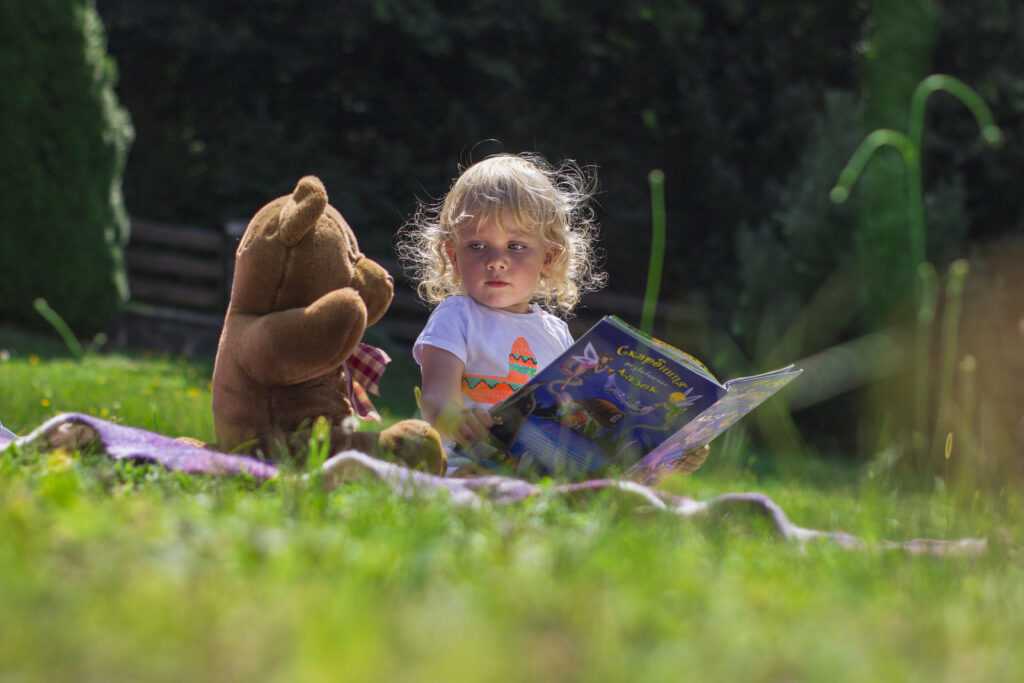 Girl sitting beside a teddy bear