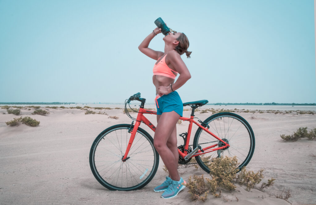 Woman drinking on black tumbler while looking up and placing her left hand on waist