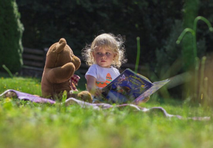 Girl sitting beside a teddy bear
