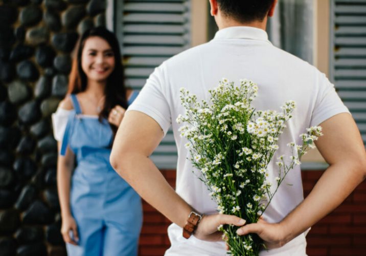 Man holding baby s breath flower in front of woman standing near marble wall